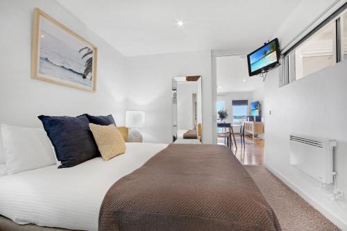 a bedroom with a large bed with a tv on the wall at 5 Knots Metung in Metung