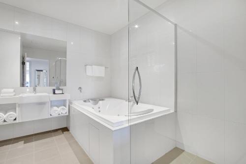 a white bathroom with a tub and a sink at 5 Knots Metung in Metung