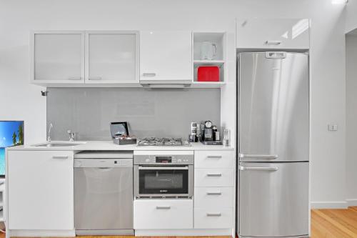a kitchen with white cabinets and a refrigerator at 5 Knots Metung in Metung