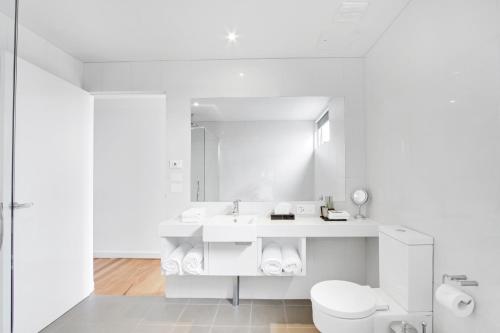 a white bathroom with a toilet and a sink at 5 Knots Metung in Metung