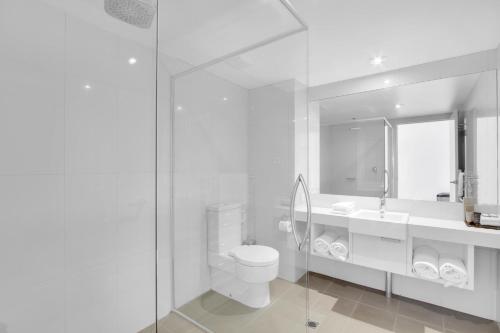 a white bathroom with a toilet and a sink at 5 Knots Metung in Metung