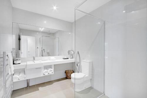 a white bathroom with a toilet and a sink at 5 Knots Metung in Metung