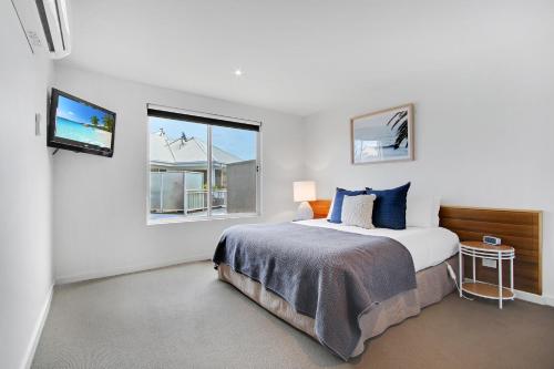 a white bedroom with a bed and two windows at 5 Knots Metung in Metung