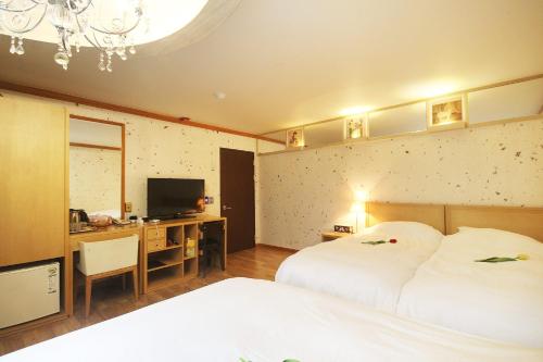 Habitación de hotel con 2 camas, escritorio y TV. en Jeonju Tourist Hotel, en Jeonju