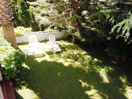two white chairs sitting in the grass in a yard at Las Araucarias in Pinamar