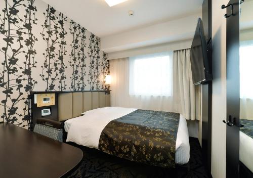 名古屋市にあるアパホテル 〈名古屋駅前南〉のベッドとテーブルが備わるホテルルームです。
