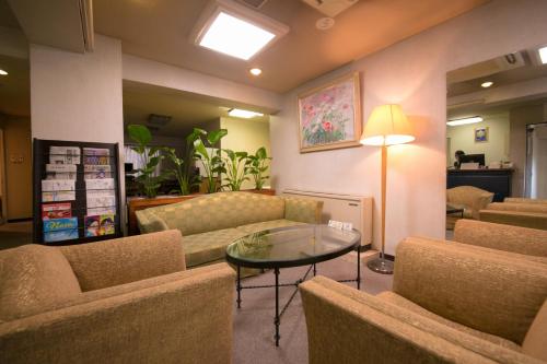 a lobby with a couch and a table and chairs at Heiwadai Hotel Arato in Fukuoka