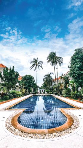 a large swimming pool with palm trees in the background at The Gardens in Bang Rak Beach