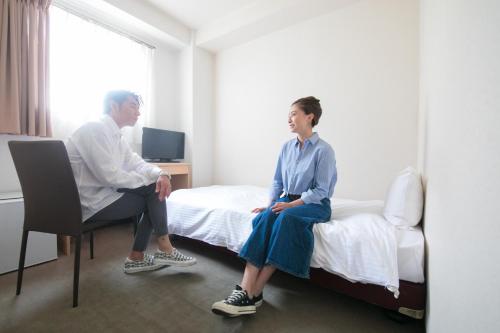 two women sitting on beds in a hospital room at Heiwadai Hotel Arato in Fukuoka