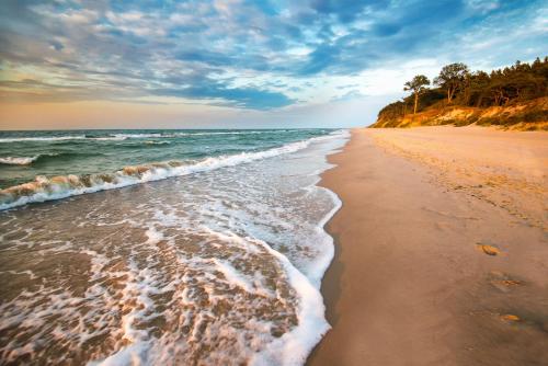 una playa con las olas entrando en Dworek Morski SPA & Wellness, en Mielno