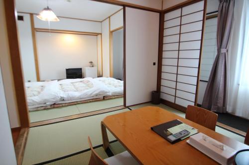 a room with a table and a bed in a mirror at Select Royal Yatsushiro in Yatsushiro