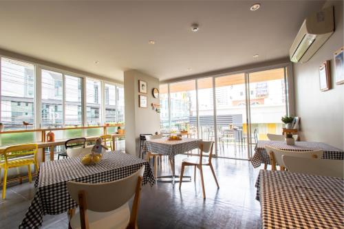 a restaurant with tables and chairs and windows at Lemontea Hotel Bangkok in Bangkok