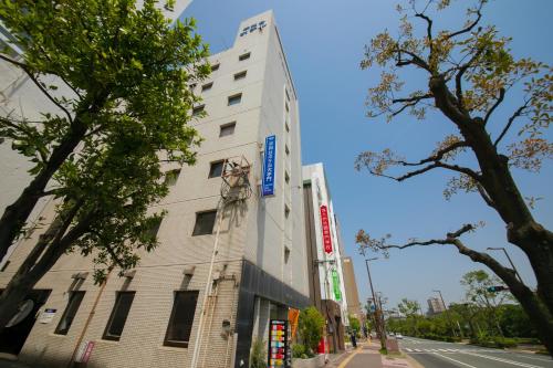 a white building with a statue on the side of it at Heiwadai Hotel Otemon in Fukuoka