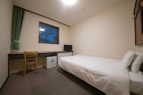 a hotel room with a bed and a desk at Heiwadai Hotel Otemon in Fukuoka