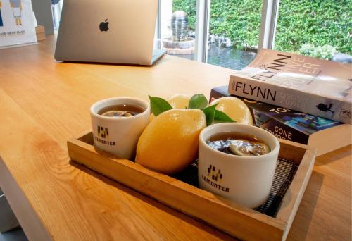 a tray with cups of coffee and oranges on a table at Lemontea Hotel Bangkok in Bangkok