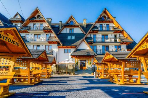 a hotel with wooden benches in front of it at Hotel Liptakówka in Białka Tatrzanska
