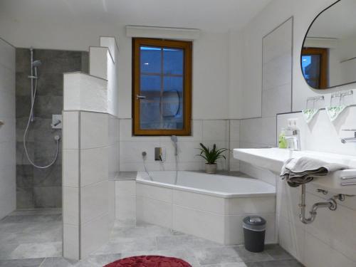 un bagno bianco con vasca e lavandino di Fischerhof a Höchenschwand