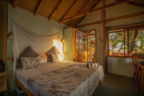 a bedroom with a bed and a large window at Goa Cottages Agonda in Agonda