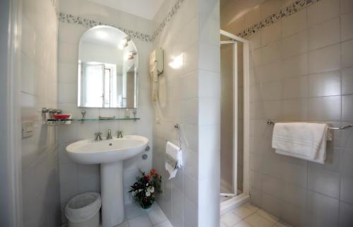 a white bathroom with a sink and a mirror at Hotel Villa Belvedere in San Gimignano