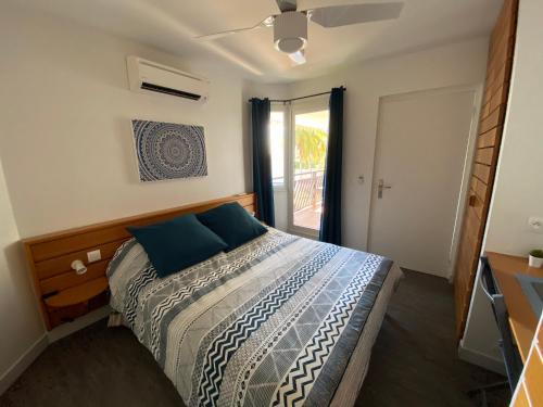 Un dormitorio con una cama con almohadas azules y una ventana en Ticarbets T3 - Résidence Manganao - En bord de Plage, en Saint-François