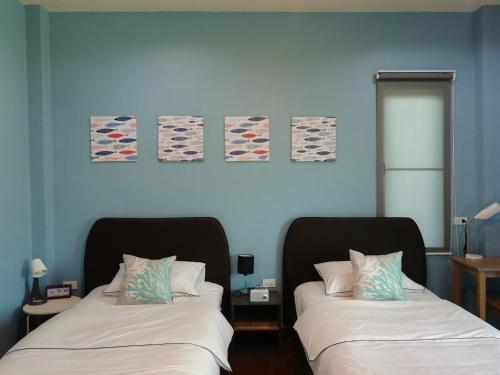 two beds in a room with blue walls at Morinaka Craftfe & Poshtel in Ban Na Muang