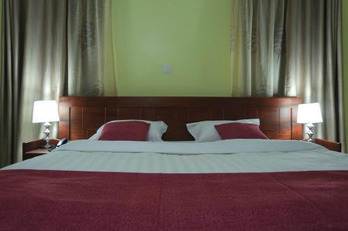 a bedroom with a large bed with two lamps at Precious Villas Lubowa in Kampala