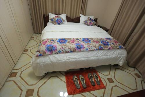 a bedroom with a large bed with shoes on it at Precious Villas Lubowa in Kampala