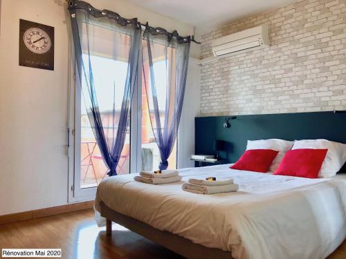 a bedroom with a large bed with red pillows and a window at Studio ToulouseCityStay Basso Cambo in Toulouse