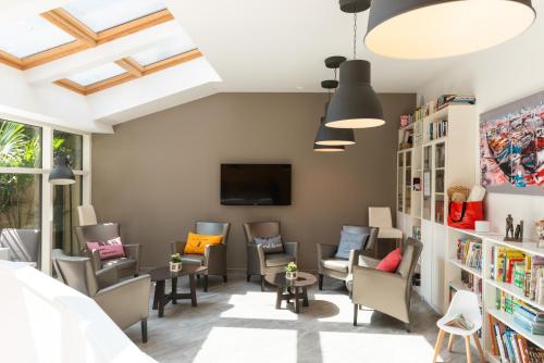 een wachtkamer met stoelen en een tv en boekenplanken bij Hôtel de la Plage in Dieppe