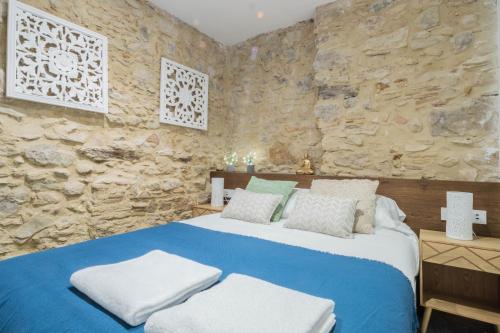 1 dormitorio con 1 cama azul y pared de piedra en Terra Boutique Apartment, en Girona