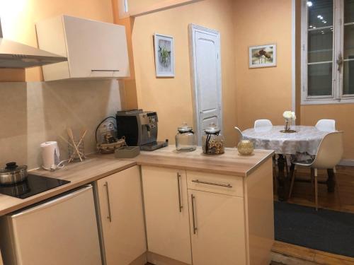 a kitchen with white cabinets and a table with a tableablish at L'hommage in Sarlat-la-Canéda