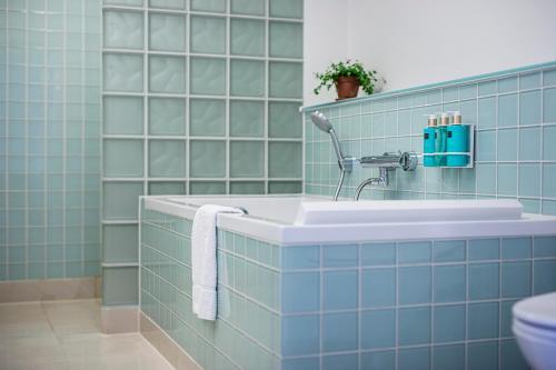 a blue tiled bathroom with a sink and a toilet at Molskroen Strandhotel in Ebeltoft