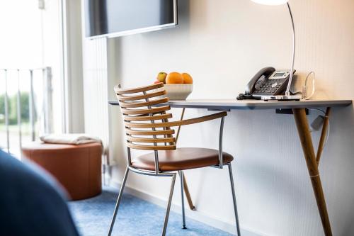 a desk with a phone and a chair in a room at Molskroen Strandhus in Ebeltoft