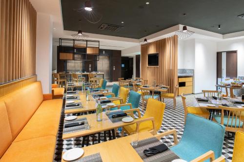 Park Inn by Radisson Gwalior في قاليور: غرفة طعام مع طاولات وكراسي خشبية