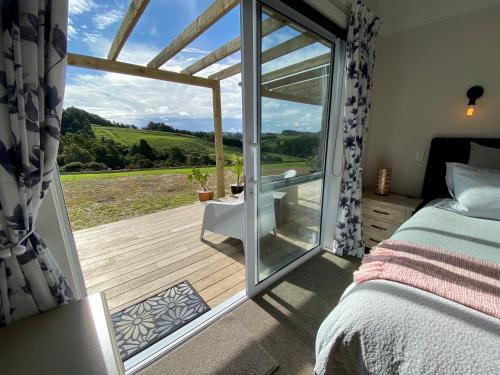 a bedroom with a bed and a sliding glass door at Kauri Glen BnB in Te Arai