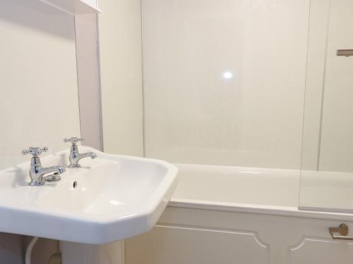 a white bathroom with a sink and a bath tub at Todlaw Farm House in Jedburgh