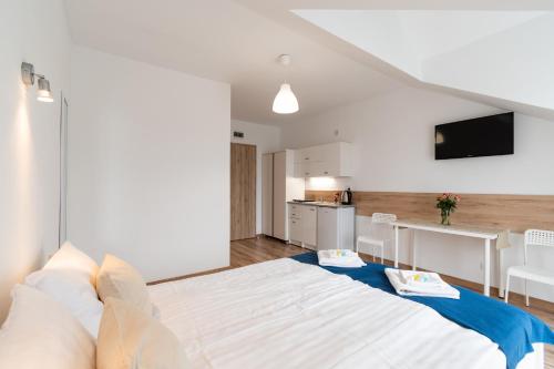 a bedroom with a large white bed and a kitchen at Willa Wena in Ustka