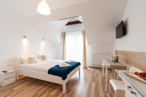 a white bedroom with a bed and a table at Willa Wena in Ustka