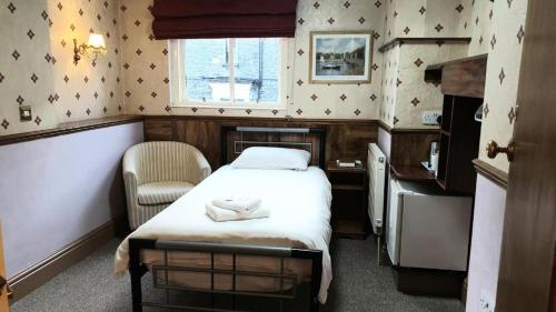 a small room with a bed and a chair at Lakes Lodge Windermere in Windermere