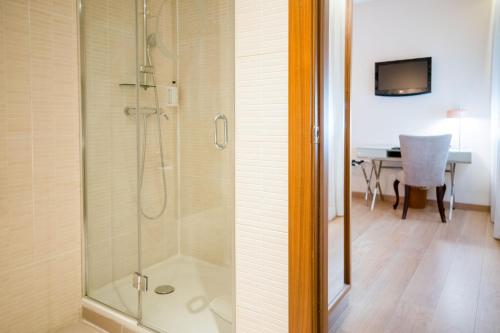 ducha con puerta de cristal junto a un baño en Hotel Opera, en Madrid
