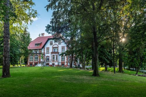 a large house in a park with trees at Hotel Villam in Bielawa
