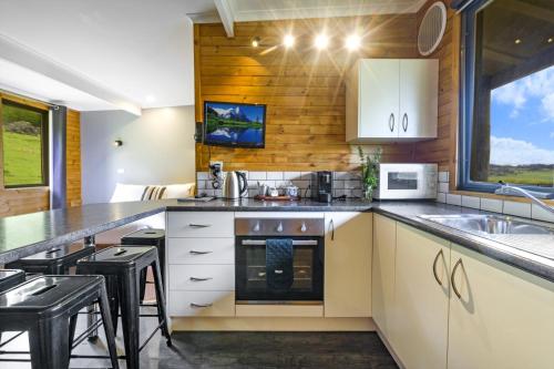 a kitchen with white cabinets and black stools at Mole Creek Cabins in Mole Creek