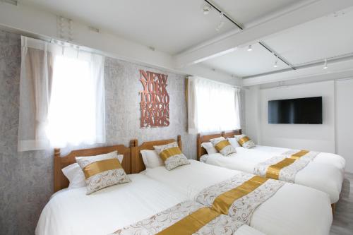 2 bedden in een kamer met witte en gele kussens bij wisdom minosima inn in Fukuoka