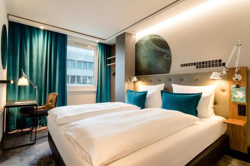 a hotel room with a large bed with blue pillows at Motel One Frankfurt Airport in Frankfurt/Main
