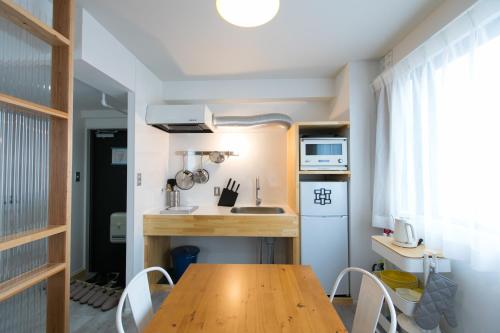 une petite cuisine avec une table et des chaises en bois dans l'établissement wisdom minosima inn, à Fukuoka