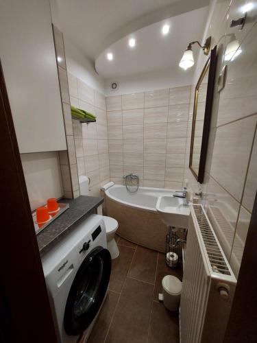a bathroom with a tub and a washing machine at Apartman Őri in Bük