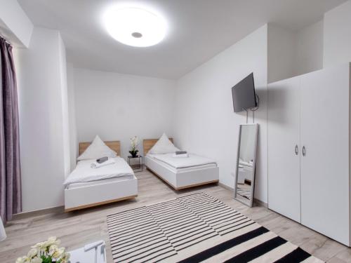 a white room with two beds and a television at Pension Amanda in Berlin
