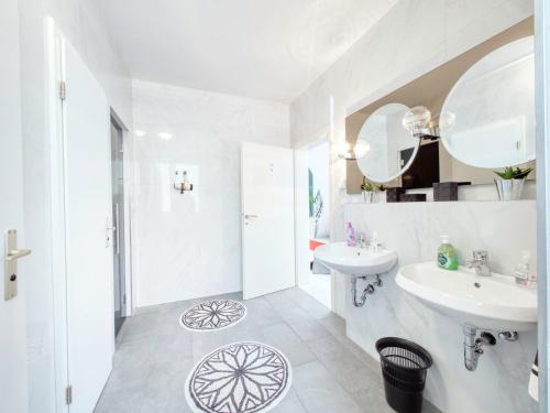 ein weißes Badezimmer mit 2 Waschbecken und einem Spiegel in der Unterkunft Pension Amanda in Berlin