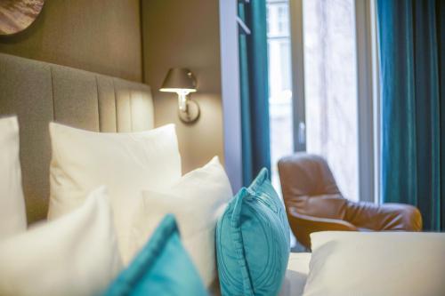 a bedroom with a bed and a chair next to a window at Motel One Lübeck in Lübeck
