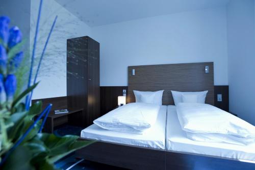 a bedroom with a large bed with white pillows at Hotel City Oase Lb in Ludwigsburg